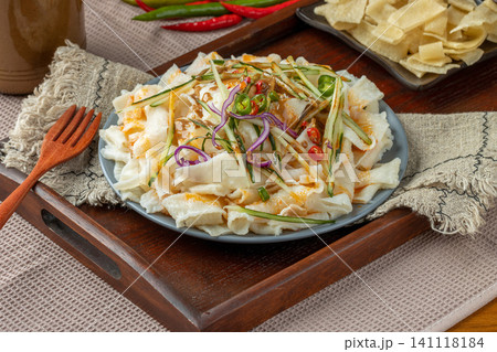 shaanxi style flavored Liangpi cold noodles with peanut sauce, cucumber, and onion on a wooden tray shaanxi style flavored Liangpi cold noodles with peanut sauce, cucumber, and onion on a wooden tray 141118184