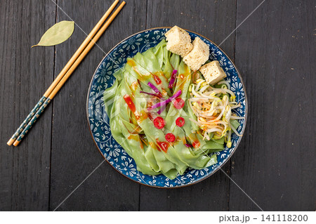 Healthy green spinach Liangpi cold noodles with bean sprouts and gluten cubes on a floral plate 141118200