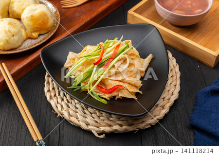shaanxi style Liangpi cold starch noodles with cucumber shreds and chili oil on a blue plate shaanxi style Liangpi cold starch noodles with cucumber shreds and chili oil on a blue plate 141118214