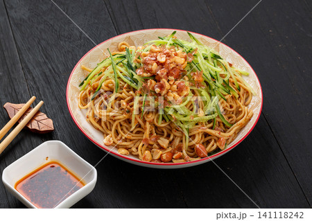 vegetarian cold noodles topped with crushed peanuts and shredded cucumber on a dark table vegetarian cold noodles topped with crushed peanuts and shredded cucumber on a dark table 141118242