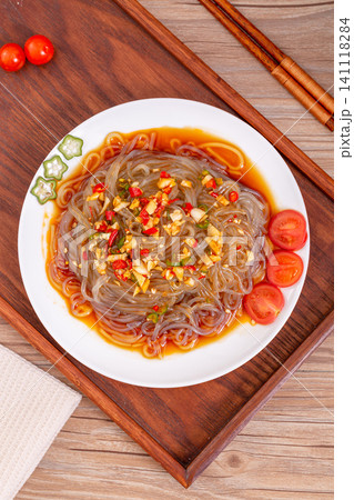spicy cold glass noodle salad with chopped chili, garlic, and cherry tomatoes on a white plate spicy cold glass noodle salad with chopped chili, garlic, and cherry tomatoes on a white plate 141118284