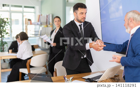 Professional adult male lawyer or bank clerk shaking hands with mature man client in bank office 141118291