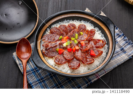 Cantonese claypot rice with sliced Chinese sausage, spoon lifting crispy scorched rice crust 141118490