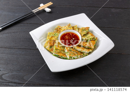 Chinese pan fried egg flatbread with chopped green chili peppers on green ceramic plate 141118574