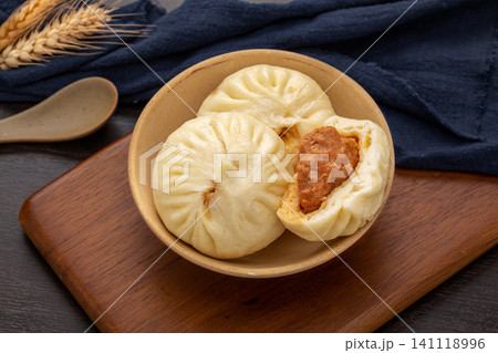 Traditional Chinese breakfast steamed meat buns served on a ceramic plate with rustic wooden decor. Traditional Chinese breakfast steamed meat buns served on a ceramic plate with rustic wooden decor. 141118996