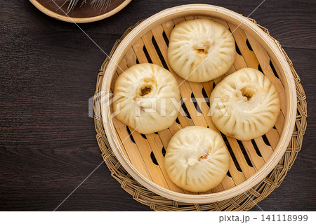 Chinese steamed pork buns (Baozi) inside a traditional bamboo steamer on a dark marble background. Chinese steamed pork buns (Baozi) inside a traditional bamboo steamer on a dark marble background. 141118999