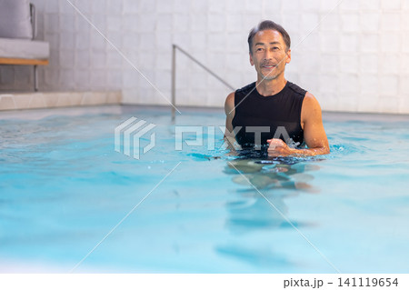 プールで水中ウォーキングをする笑顔のシニア男性 141119654