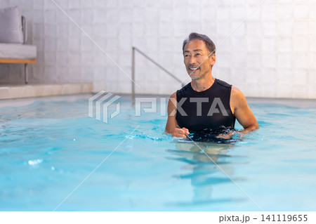 プールで水中ウォーキングをする笑顔のシニア男性 141119655