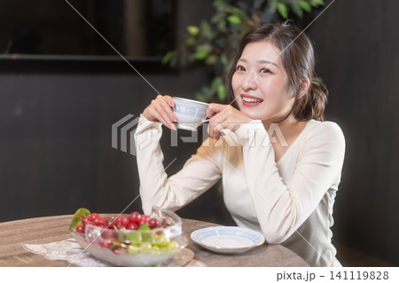 コーヒーを飲んでリラックスする笑顔の若い女性 コーヒーを飲んでリラックスする笑顔の若い女性 141119828