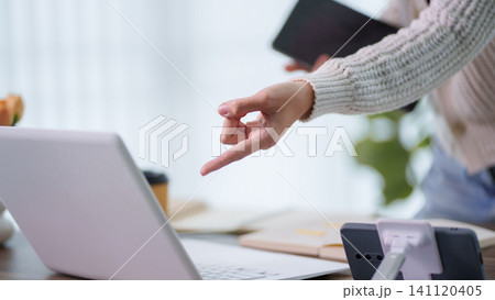 Woman pointing at laptop screen during online education tutorial session in bright home office with copy space Woman pointing at laptop screen during online education tutorial session in bright home office with copy space 141120405