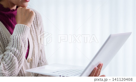 Young adult woman in beige sweater holding laptop while studying or working remotely at bright home workspace with copy space Young adult woman in beige sweater holding laptop while studying or working remotely at bright home workspace with copy space 141120408
