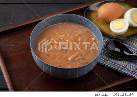 traditional Chinese savory millet porridge Doumo in a blue ceramic bowl, served with boiled eggs for breakfast. traditional Chinese savory millet porridge Doumo in a blue ceramic bowl, served with boiled eggs for breakfast. 141121134