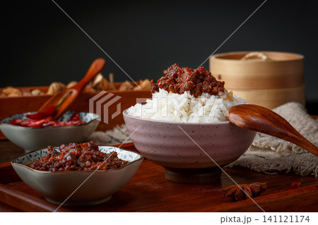 A bowl of steamed rice topped with savory beef chili sauce, traditional Chinese condiment. A bowl of steamed rice topped with savory beef chili sauce, traditional Chinese condiment. 141121174