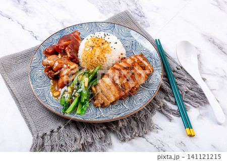 braised pork feet and sliced pork belly combo rice with green vegetables on a decorative plate. 141121215