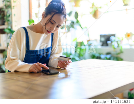 スマホでカード決済する若い日本人女性 スマホでカード決済する若い日本人女性 141121625