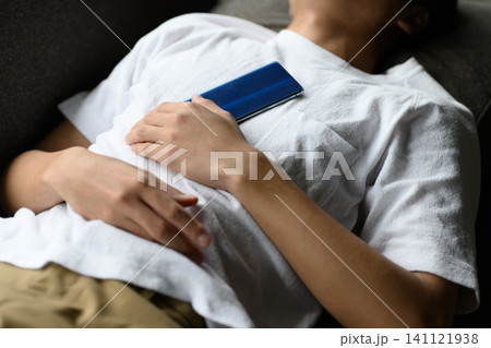 ソファで眠る男性と胸の上のスマホ ソファで眠る男性と胸の上のスマホ 141121938