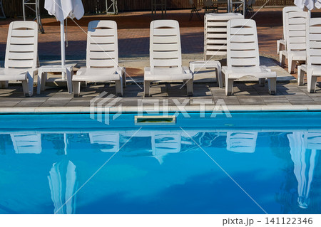 Summer relax.Outdoor pool at the resort with sun loungers Summer relax.Outdoor pool at the resort with sun loungers 141122346