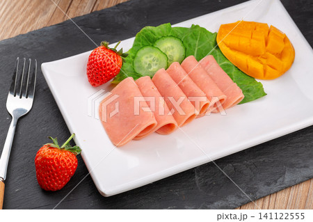 sliced square luncheon meat with fresh lettuce and strawberry on white plate sliced square luncheon meat with fresh lettuce and strawberry on white plate 141122555