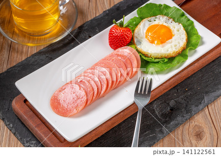 breakfast set with sliced round ham, fried egg, strawberry and tea breakfast set with sliced round ham, fried egg, strawberry and tea 141122561
