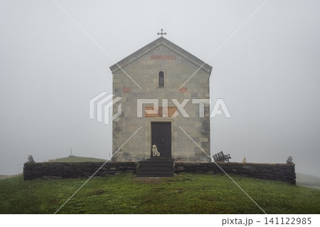 Small stone church in the mountains in foggy weather with dogs, Georgia Small stone church in the mountains in foggy weather with dogs, Georgia 141122985