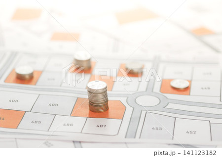 A pile of Coins is placed on the land map. choose the land location building plot for house construction. real estate concept with vacant land for building construction for sale, rent, buy, investment 141123182