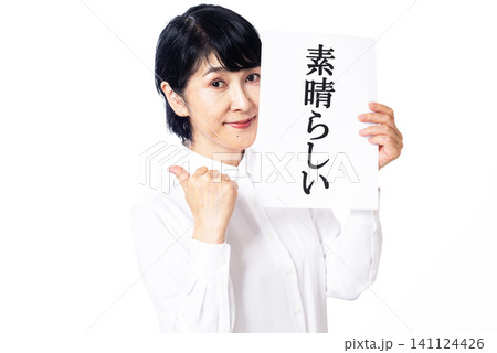 素晴らしいと書かれた紙を持ちカメラ目線で微笑む白いシャツを着た中年女性 素晴らしいと書かれた紙を持ちカメラ目線で微笑む白いシャツを着た中年女性 141124426