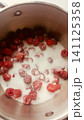 Top-down view of fresh red raspberries and white granulated sugar inside a stainless steel cooking pot, ready for making jam. 141125358