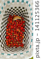 Top-down view inside a checkered woven basket filled with freshly picked red strawberries and one wild mushroom. 141125366