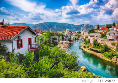 Amazing Skyline of Mostar with the Mostar Bridge, houses and minarets, during sunny day Amazing Skyline of Mostar with the Mostar Bridge, houses and minarets, during sunny day 141125677