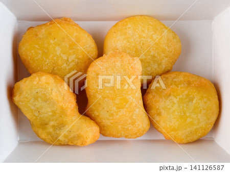 Crispy golden chicken nugget in white paper takeout container top view extreme close up flat lay delicious savory meat junk food snack Crispy golden chicken nugget in white paper takeout container top view extreme close up flat lay delicious savory meat junk food snack 141126587
