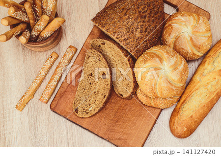 French baguettes. Fresh crispbread. Bread background. Different breed on wooden background. French baguettes. Fresh crispbread. Bread background. Different breed on wooden background. 141127420