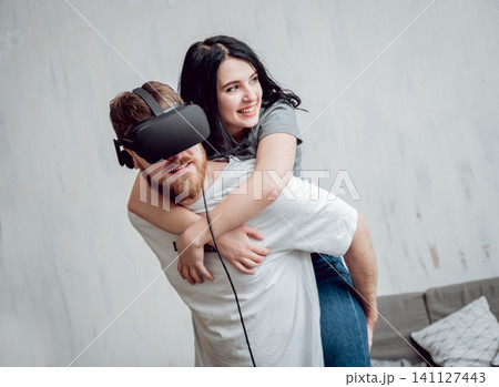 The young man with girlfriend playing games with virtual reality goggles The young man with girlfriend playing games with virtual reality goggles 141127443