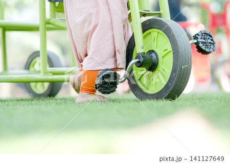 Detail of Child's Legs on Green Ride-On Toy Detail of Child's Legs on Green Ride-On Toy 141127649