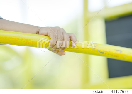 Close-Up of Child's Hand Holding Yellow Playground Bar Close-Up of Child's Hand Holding Yellow Playground Bar 141127658