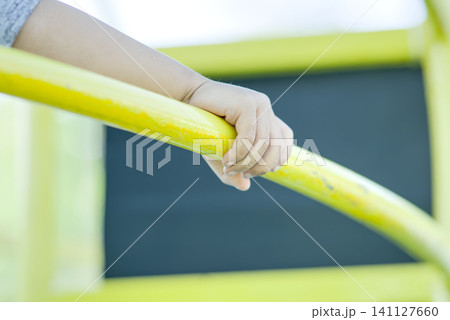 Close-Up of Child's Hand Holding Yellow Playground Bar	 141127660