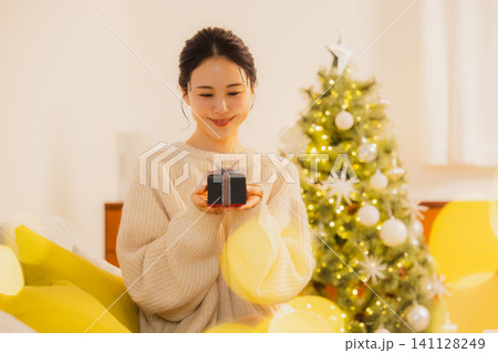 クリスマスプレゼントを渡す若い女性 141128249