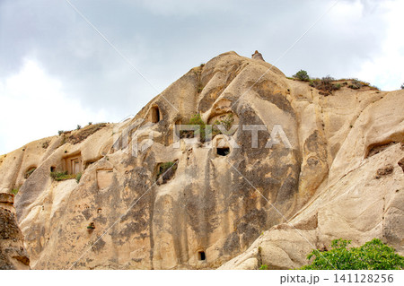 Rock formations with ancient cave dwellings in a mountainous area at a cloudy time of day Rock formations with ancient cave dwellings in a mountainous area at a cloudy time of day 141128256