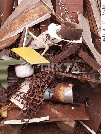 Pile of rusty scrap metal with discarded steel sheets, pipes, wire, household items and industrial waste at a recycling yard. Concept of metal recycling, waste management, environmental pollution, ind Pile of rusty scrap metal with discarded steel sheets, pipes, wire, household items and industrial waste at a recycling yard. Concept of metal recycling, waste management, environmental pollution, ind 141128265