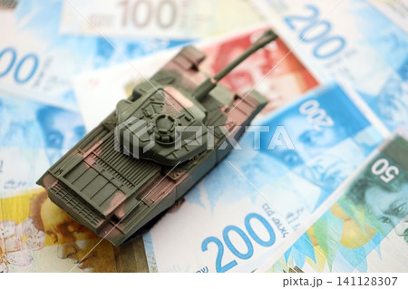 Israel New Shekels banknotes and toy tank. The current Israel money bills and tank lies on table Israel New Shekels banknotes and toy tank. The current Israel money bills and tank lies on table 141128307