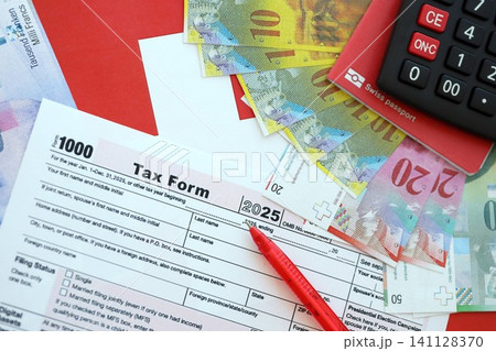 Swiss franc banknotes and tax form with pen. The current francs money bills lies on tax return form 141128370