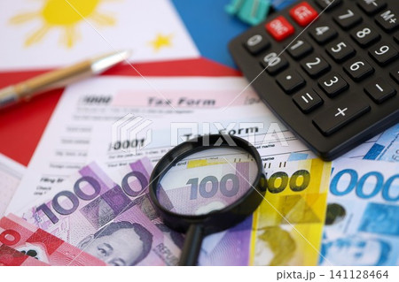 Philippines peso money bills and calculator with tax form on flag. Taxation and accounting concept Philippines peso money bills and calculator with tax form on flag. Taxation and accounting concept 141128464