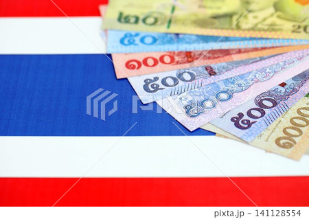 Thai baht currency money bills lies on flag. The concept of business and investment Thai baht currency money bills lies on flag. The concept of business and investment 141128554