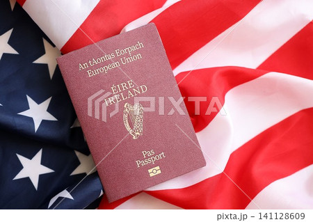 Ireland passport on big waving flag of United States of America. US Visa and immigration Ireland passport on big waving flag of United States of America. US Visa and immigration 141128609