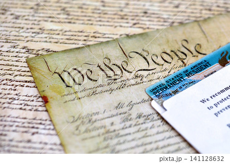 Permanent resident green card in envelope lies on US constitution page Permanent resident green card in envelope lies on US constitution page 141128632