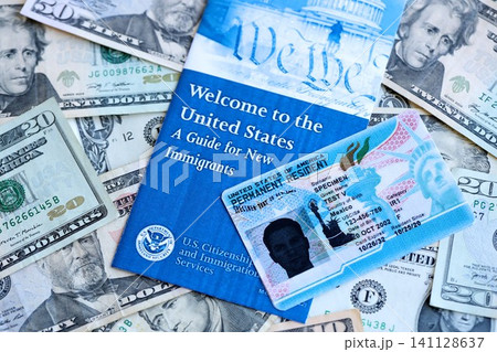 Permanent resident green card and guide for new immigrants lies on many dollar bills Permanent resident green card and guide for new immigrants lies on many dollar bills 141128637
