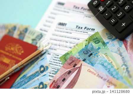 Bahraini dinar money bills and calculator with tax form on blue. Taxation and accounting concept Bahraini dinar money bills and calculator with tax form on blue. Taxation and accounting concept 141128680