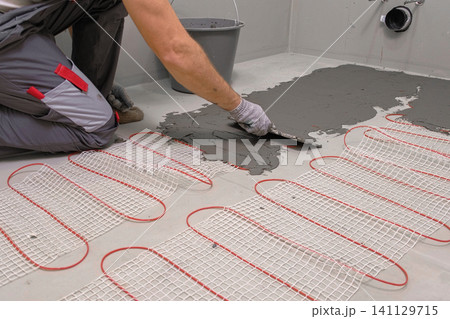 Electric Heating Mat Installing in the Tile Adhesive. Underfloor Dual Core Fiberglass Mesh Mat. Warm Floor Heating System. Warming. Worker Applying Concrete Mortar for Warm Floor. Renovation work. 4K Electric Heating Mat Installing in the Tile Adhesive. Underfloor Dual Core Fiberglass Mesh Mat. Warm Floor Heating System. Warming. Worker Applying Concrete Mortar for Warm Floor. Renovation work. 4K 141129715