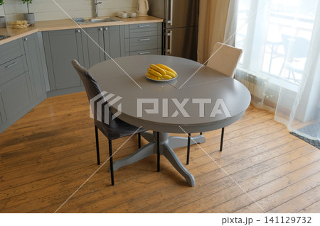 Dining room interior. Gray oval dining table, wood flooring, grey cabinets. Interior design of stylish kitchen with family table, modern chairs. Wooden floor. White wall. Template. New Luxury Home. 141129732