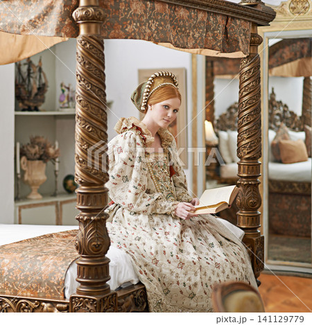 Woman, queen and book with portrait for renaissance, royalty aesthetic and reading in palace bedroom. Monarch, wealthy person and elegant dress for cosplay, regal and medieval knowledge in the castle Woman, queen and book with portrait for renaissance, royalty aesthetic and reading in palace bedroom. Monarch, wealthy person and elegant dress for cosplay, regal and medieval knowledge in the castle 141129779