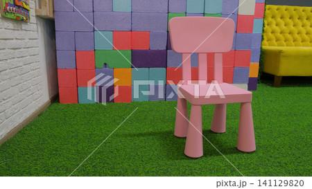 Colorful plastic kids chair. Pink children's chair in child room. Space for text. Stool for children in bright vivid playroom. Furniture for baby toddlers. Kindergarten preschool classroom concept Colorful plastic kids chair. Pink children's chair in child room. Space for text. Stool for children in bright vivid playroom. Furniture for baby toddlers. Kindergarten preschool classroom concept 141129820